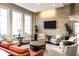 Comfortable lounge area featuring multiple chairs, couch, stone wall, tv, and large windows at 19241 Serafina St, Venice, FL 34293