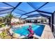 Screened-in pool area with clear blue water, ample seating, and tropical landscaping at 1960 Mississippi Ave, Englewood, FL 34224