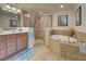 A well-lit bathroom featuring a soaking tub, glass-enclosed shower, and double vanity with granite countertops at 20110 Ragazza Cir # 102, Venice, FL 34293