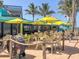 Restaurant's outdoor seating area under yellow umbrellas, next to the beach, and palm trees at 20110 Ragazza Cir # 102, Venice, FL 34293