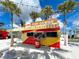 Exterior view of Pop Dawgs featuring a colorful, eye-catching design surrounded by palm trees and outdoor seating at 20110 Ragazza Cir # 102, Venice, FL 34293