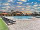 Resort-style pool with sun loungers and orange umbrellas under a partly cloudy, blue sky at 20110 Ragazza Cir # 102, Venice, FL 34293