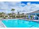 A large community pool features comfortable lounge chairs, umbrellas, and manicured green space at 2088 Bonito Way, Port Charlotte, FL 33953