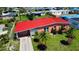 An aerial view of a charming residence featuring a red metal roof, a well-manicured lawn, and mature landscaping at 22032 Felton Ave, Port Charlotte, FL 33952