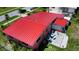 An aerial view of a residence showcasing a striking red metal roof, patio, and well-kept backyard at 22032 Felton Ave, Port Charlotte, FL 33952