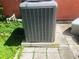 Close-up of an air conditioning unit with a hurricane sticker on concrete pavers with some greenery behind it at 22032 Felton Ave, Port Charlotte, FL 33952