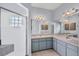 Primary bathroom with tiled shower, double sink vanity, and modern lighting at 224 Pine Glen Ct, Englewood, FL 34223