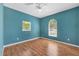 A bedroom with teal walls, wood floors, a ceiling fan, and two windows at 224 Pine Glen Ct, Englewood, FL 34223