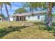 Lush front lawn surrounds home with a well-kept exterior with painted accents and shade tree at 224 Pine Glen Ct, Englewood, FL 34223