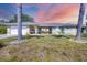 Charming home featuring a manicured lawn, front-facing garage, and colorful facade enhanced by vibrant landscaping at 224 Pine Glen Ct, Englewood, FL 34223