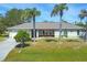 Charming one-story home with lush lawn and two palm trees framing the entryway at 224 Pine Glen Ct, Englewood, FL 34223