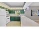 Traditional kitchen with green cabinets, white appliances, tile floor and a breakfast bar at 224 Pine Glen Ct, Englewood, FL 34223