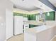 Kitchen featuring white appliances, green cabinets, and a breakfast bar at 224 Pine Glen Ct, Englewood, FL 34223