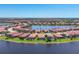 An expansive aerial view showcasing a community nestled around a lake, featuring tiled-roof homes at 23781 Waverly Cir, Venice, FL 34293