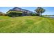 Well-manicured lawn leading to a screened-in lanai with lake views, offering privacy and outdoor living at 23781 Waverly Cir, Venice, FL 34293