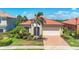 Charming home with lush landscaping, a terracotta roof, brick driveway, and a welcoming two-car garage at 23781 Waverly Cir, Venice, FL 34293