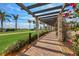 Scenic walkway with a pergola, lush greenery, and vibrant flowers by the side at 23781 Waverly Cir, Venice, FL 34293