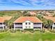 Aerial showcasing multi-story homes with screened patios and vibrant green surroundings and tile roofs at 4624 Club Dr # G201, Port Charlotte, FL 33953