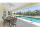 Outdoor dining table is seated beside a pristine pool with a screened-in enclosure and picturesque natural views at 48 Par View Ct, Rotonda West, FL 33947