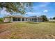 A large backyard showcases the sunroom and screened pool enclosure, creating an inviting space for outdoor living at 7151 Cork Ln, Englewood, FL 34224