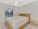 This bedroom features a light wood bed frame, a ceiling fan, and a window for plenty of natural light at 7151 Cork Ln, Englewood, FL 34224