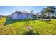 Landscaped backyard with a modern home in the background under a bright blue sky at 7499 Ashtabula St, Englewood, FL 34224