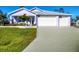 Charming one-story home featuring a three-car garage, manicured lawn, and a delightful, light purple exterior at 7499 Ashtabula St, Englewood, FL 34224