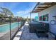 Poolside view showcases hot tub and patio under a corrugated awning, enclosed by a safety fence at 8164 Archie St, Englewood, FL 34224