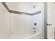Bright bathroom featuring a white tub with tiled walls and stylish gray accent stripe at 8375 E Windbound Ct Ct, Sarasota, FL 34240