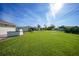 Large backyard with lush green grass and an outdoor kitchen area; the yard extends to the neighboring properties at 9423 El Campo Ave, Englewood, FL 34224