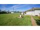 Backyard features lush green grass, landscaping, and an outdoor water pump feature; the yard extends to the neighboring houses at 9423 El Campo Ave, Englewood, FL 34224