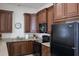 Kitchen featuring brown cabinets, black appliances, and a neutral countertop at 10310 Coral Landings Ct # 98, Placida, FL 33946