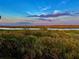Scenic water view showcasing lush vegetation and a tranquil river under a beautiful, colorful sky at 10310 Coral Landings Ct # 98, Placida, FL 33946