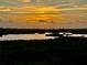 Stunning sunset water view, featuring a golden sky reflecting on a serene lake surrounded by lush greenery at 10310 Coral Landings Ct # 98, Placida, FL 33946