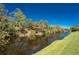 Picturesque canal view with lush vegetation along the banks, reflecting the clear blue sky above at 10308 Euston Ave, Englewood, FL 34224