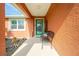 Welcoming front porch area with seating, decorative plants, and a charming green front door at 1080 Panda Rd, Venice, FL 34293
