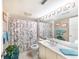 Cozy bathroom with floral shower curtain, white vanity with marble countertop, and a large framed mirror at 11000 Placida Rd # 702, Placida, FL 33946