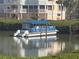 A blue pontoon boat is docked in a canal with the building in the background at 11000 Placida Rd # 702, Placida, FL 33946