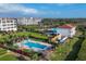 Aerial view showcasing luxury resort pool and club house with nearby condos, palm trees, and lush lawns at 11140 Hacienda Del Mar Blvd # E-301, Placida, FL 33946