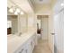 Bright bathroom with dual sinks, a large mirror, white cabinets, and a doorway to a walk-in shower at 127 White Marsh Ln, Rotonda West, FL 33947