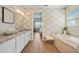 Inviting bathroom featuring a soaking tub, double sinks, patterned wallpaper, and a serene ambiance at 1409 Remington Trace Dr, Port Charlotte, FL 33953