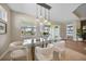 Sunlit dining room featuring a modern chandelier and large windows with views of the landscaped yard at 1409 Remington Trace Dr, Port Charlotte, FL 33953