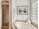 Luxurious primary bathroom featuring a tiled shower, soaking tub, and glass block window for natural light at 15578 Seafoam Cir, Port Charlotte, FL 33981