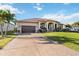 Wide driveway leading to a welcoming home with lush landscaping and an attached two-car garage at 15578 Seafoam Cir, Port Charlotte, FL 33981