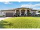 Beautiful home exterior featuring a manicured lawn, arched entryway, and attached two car garage at 15578 Seafoam Cir, Port Charlotte, FL 33981