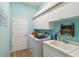 Functional laundry room with blue walls, white cabinetry, a utility sink, and included washer and dryer at 15578 Seafoam Cir, Port Charlotte, FL 33981
