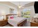 Bright main bedroom boasts large arched window with shutters and neutral decor and ceiling fan at 15578 Seafoam Cir, Port Charlotte, FL 33981