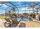 Serene pool and spa area inside a screened enclosure, complete with lounge chairs and tropical landscaping at 15578 Seafoam Cir, Port Charlotte, FL 33981