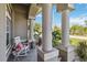 Inviting front porch with rocking chair, complemented by decorative columns and lush greenery at 15578 Seafoam Cir, Port Charlotte, FL 33981