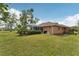 Expansive backyard featuring lush green grass, mature trees, and a screened-in lanai perfect for outdoor living at 16137 Alcira Cir, Punta Gorda, FL 33955